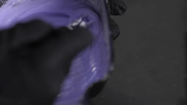 El peluquero mezcla tinte de pelo azul / púrpura en un tazón negro . — Vídeo de stock
