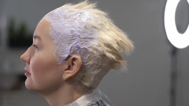 Профіль дівчини під час фарбування волосся в салоні краси . — стокове відео