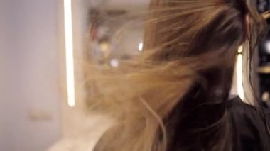 Kuaförün kuaföründe saç kurutma makinesiyle kurutmak. Saçlar kameraya doğru uçuyor.