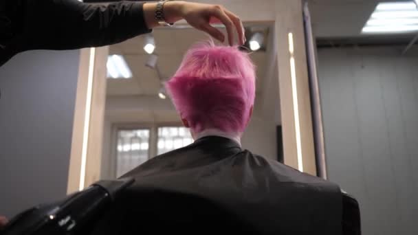 Les cheveux courts roses sont séchés à l'air libre dans une salon.Vue arrière d'en bas. Mouvement lent — Video