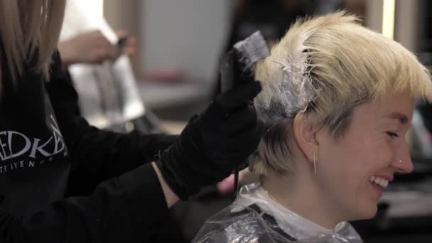 Close-up of stylist hands using professional hairbrush and dyeing hair roots — Stockvideo