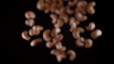 Kaju, siyah arka planda bir aşağı bir yukarı uçar. Kaju fıstıklı sağlıklı yemek pişirmek