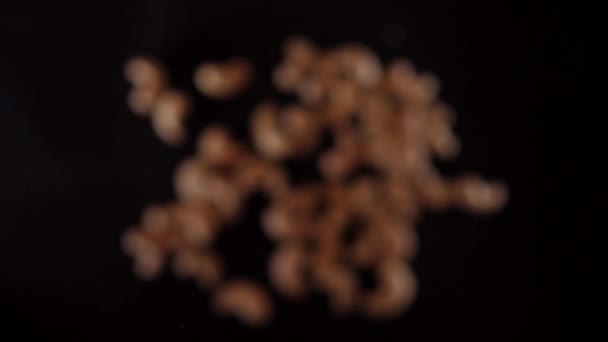 Cashew vliegt op en neer op een zwarte achtergrond. Gezond eten koken met cashew — Stockvideo