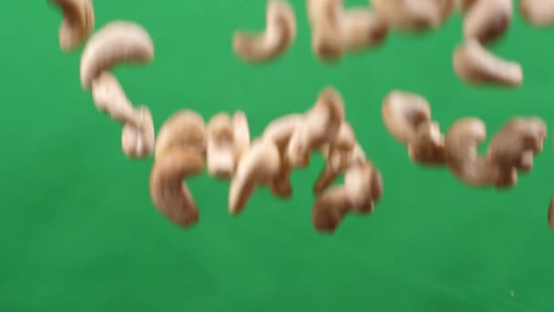 Cashew flyger upp och ner på en grön bakgrund. Matlagning hälsosam mat med cashew — Stockvideo