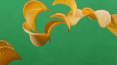 Patates cipsi yeşil arka planda serbest düşüşte. Ağır çekim. Pringles