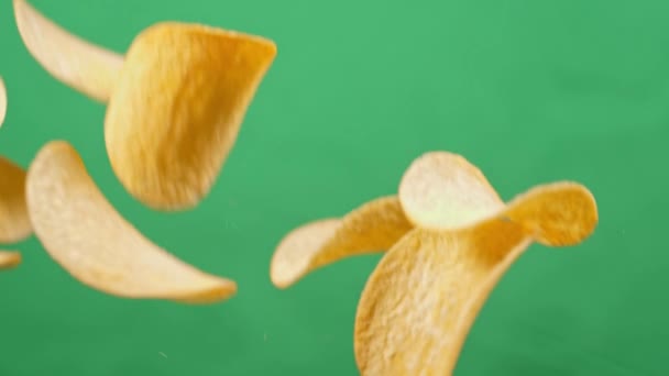 Картофельные чипсы в свободном падении на зеленом фоне. Медленное движение. Принглс — стоковое видео