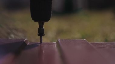 Kırmızı metal kiremitleri vidayla birbirine bağlıyorum. Çatıyı bağla