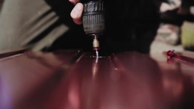 Kırmızı metal kiremitleri vidayla birbirine bağlıyorum. Çatıyı bağla