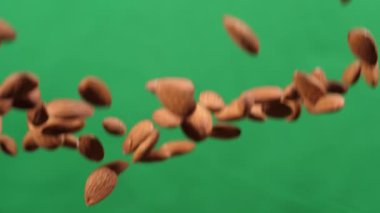 Bademler yeşil arka planda bir aşağı bir yukarı uçar. Bademlerle sağlıklı yemekler pişirirler..