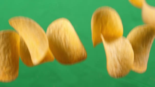 Kartoffelchips im freien Fall auf grünem Hintergrund. Zeitlupe. Pringles — Stockvideo