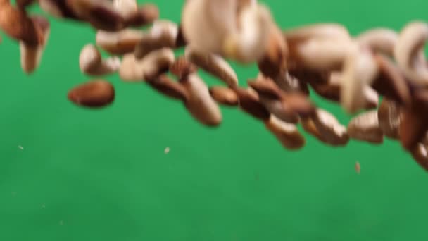 Mélange de noix voler de haut en bas sur un fond vert. Cuisiner des aliments sains avec un mélange de noix — Video