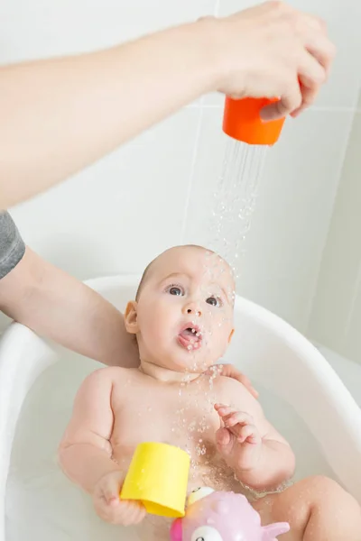 Sieben Monate altes Mädchen in einer Badewanne, spielt mit rosa Spielzeug und — Stockfoto
