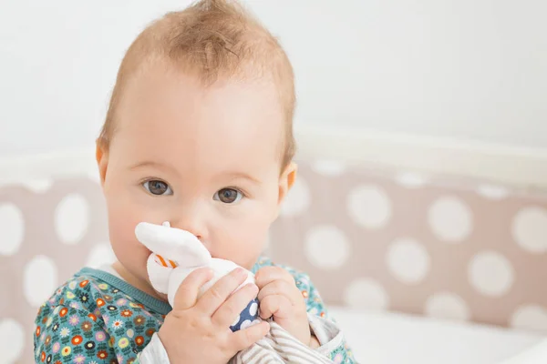 Acht Monate altes Mädchen lutscht ihr Kaninchen-Spielzeug in ihrem Bett — Stockfoto