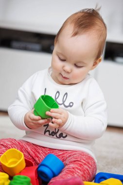 Dokuz aylık bebek kız yere onun oyuncakları ile oynarken 