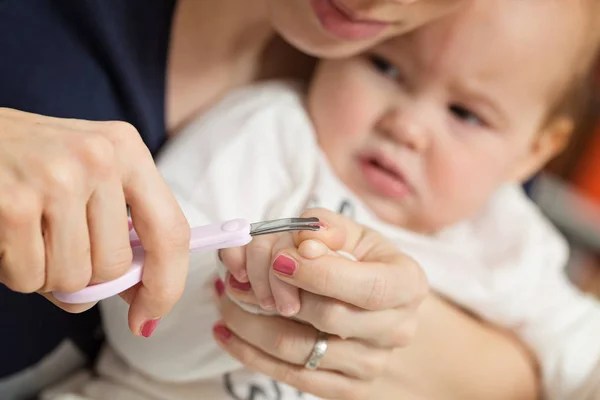 Mutter schneidet Fingernägel ihres neun Monate alten Mädchens — Stockfoto