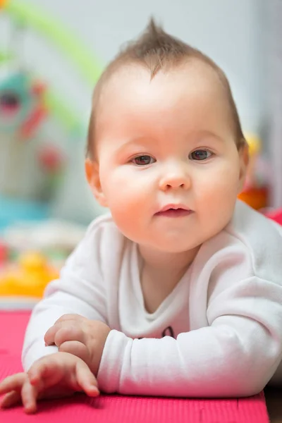 Niña de ocho meses acostada sobre su vientre en la alfombra del piso , — Foto de Stock