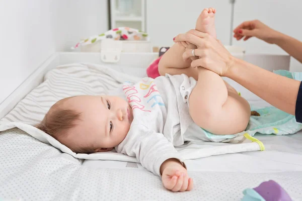 Mother changing diapers of a nine months old baby girl daughter — Stock Photo, Image