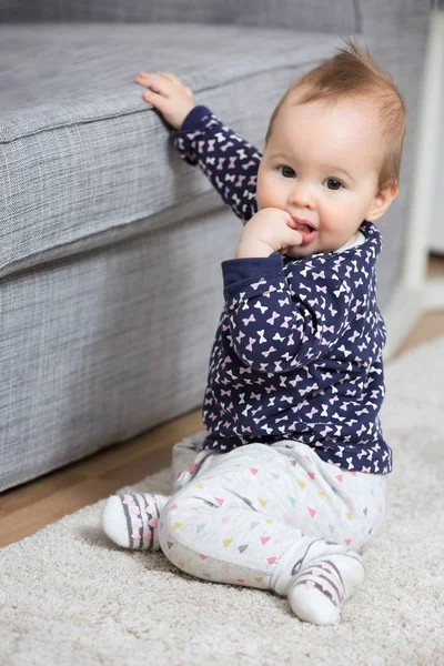 Neun Monate altes Mädchen sitzt auf dem Boden neben dem Sofa — Stockfoto