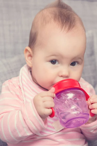 Bebé bebiendo agua de la botella de plástico rojo, sentado en — Foto de Stock