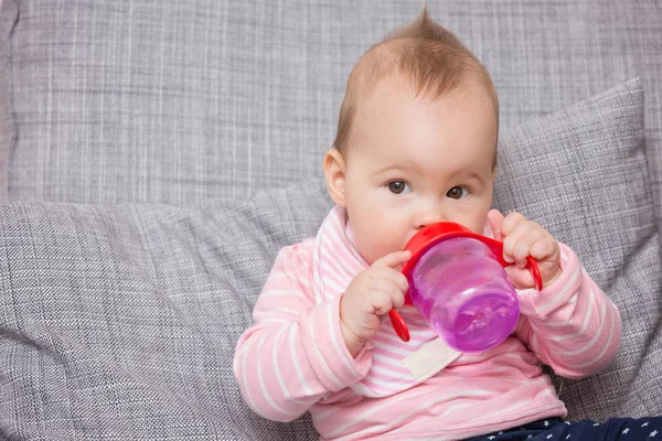 Bebé niña bebiendo agua de la botella de plástico rojo — Foto de Stock