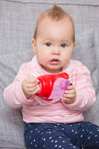 Bebé niña bebiendo agua de la botella de plástico rojo — Foto de Stock