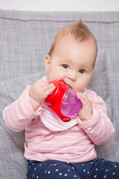 Baby girl a piros műanyag palack ivóvíz — Stock Fotó