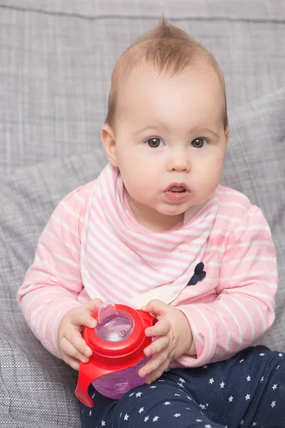 Babymädchen trinkt Wasser aus der roten Plastikflasche — Stockfoto