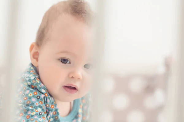 Bébé fille de huit mois dans son lit, regardant à travers les bars — Photo