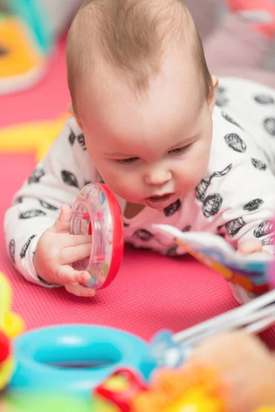 Niña de ocho meses jugando con juguetes coloridos en el suelo — Foto de Stock