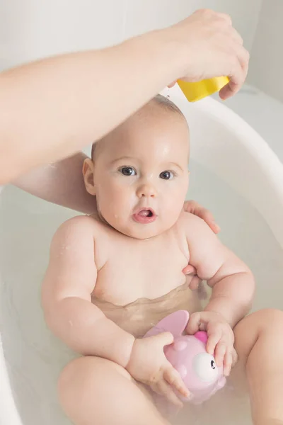 Bambina di sette mesi in un bagno, giocando con il giocattolo rosa — Foto Stock