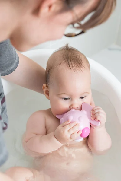 Siete meses niña en un baño, jugando con el juguete rosa y — Foto de Stock