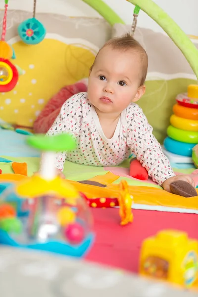 Osm měsíců starou holčičku hraje s barevnými hračkami na podlaze Royalty Free Stock Obrázky