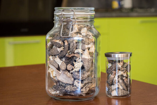 Dried morels in glasses on wooden table in kitchen