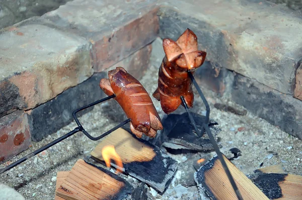 Two grilling sausage over a fire in summer — Stock Photo, Image