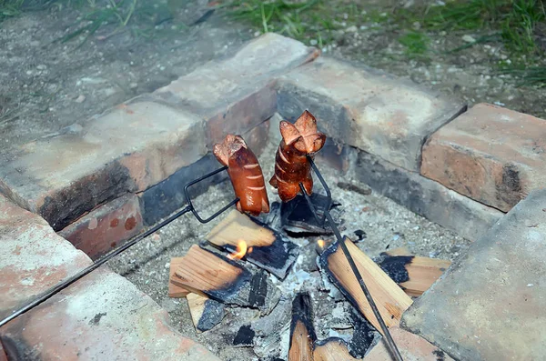 Two grilling sausage over a fire in summer — Stock Photo, Image