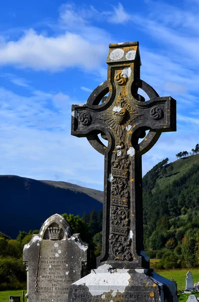 Altes irisches keltisches Steinkreuz auf Friedhof bei blauem Himmel — Stockfoto