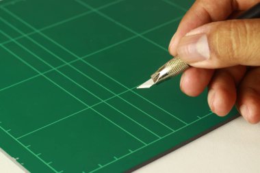 Paspasın tepesinde bir el ile tutulan kalem kesicisi.