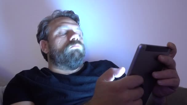 男はデジタルタブレットを使用してベッドでリラックス — ストック動画