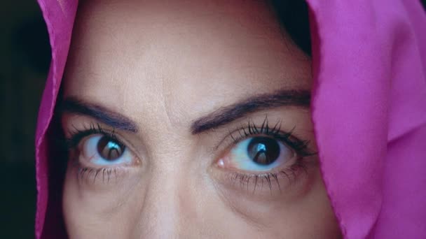 黒目の女性でピンクのスカーフ見ますザカメラ クローズアップ撮影上の彼女の黒目 — ストック動画