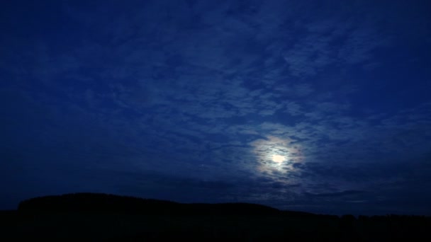 Timelapse: tajemniczy księżyc ukrywający się za chmurami, świecący jasno na ciemnym niebie — Wideo stockowe