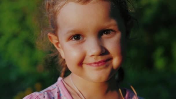 Menina bonito com olhos castanhos olhando para a câmera e sorrindo — Vídeo de Stock