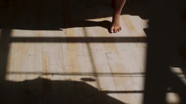 Les pieds féminins vont sur le sol en bois coulant une ombre — Video