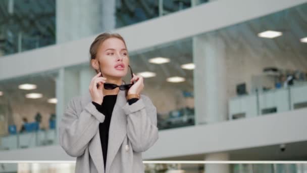 Modieuze blonde haar jonge vrouw met een zonnebril en kijken naar de camera — Stockvideo