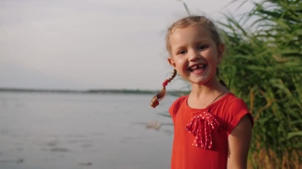 Porträt eines süßen kleinen Mädchens blickt in die Kamera und lächelt — Stockvideo
