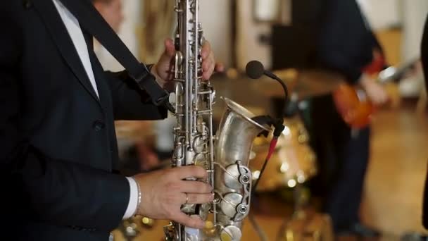 Musician wearing black suit plays saxophone on scene. Jazz band playing. — Stock Video