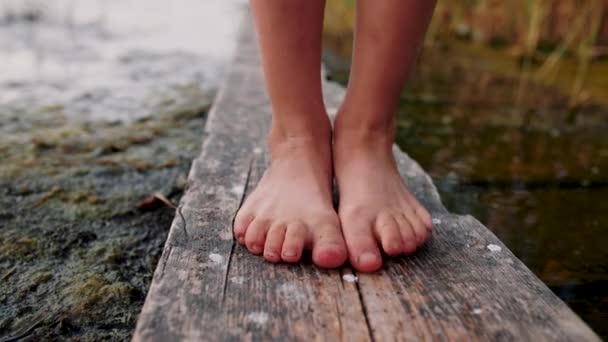 Piedi bambina in piedi su tavola di legno e dita dei piedi si muovono. Sullo sfondo del lago — Video Stock
