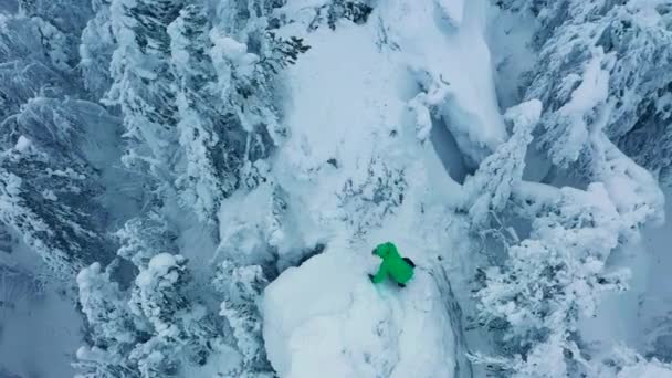 Mannen klättrar på bergstoppen och gläds åt framgången. Vild snöig skog runt — Stockvideo