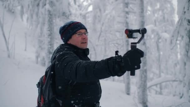 Чоловік мандрівник блогер записує відеофільм на екшн-камеру в зимовому лісі — стокове відео