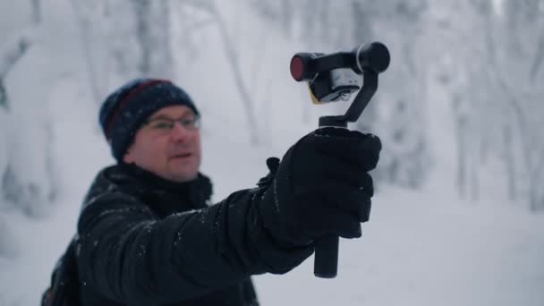 आदमी यात्री ब्लॉगर शीतकालीन जंगल में एक्शन कैम पर वीडियो फिल्म रिकॉर्ड करता है — स्टॉक वीडियो
