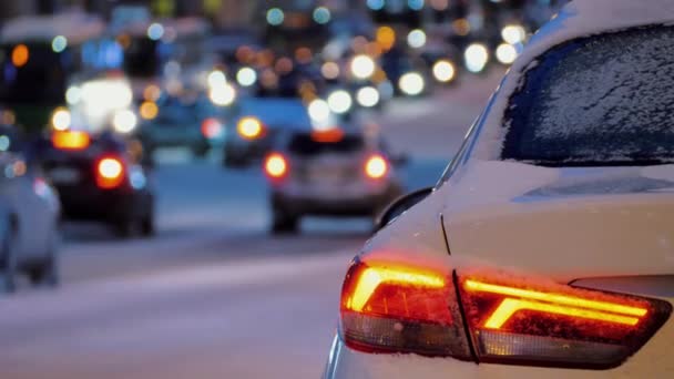 Atrás del coche estacionado en el fondo del tráfico de coches de la ciudad, luces traseras del coche están encendidas — Vídeo de stock